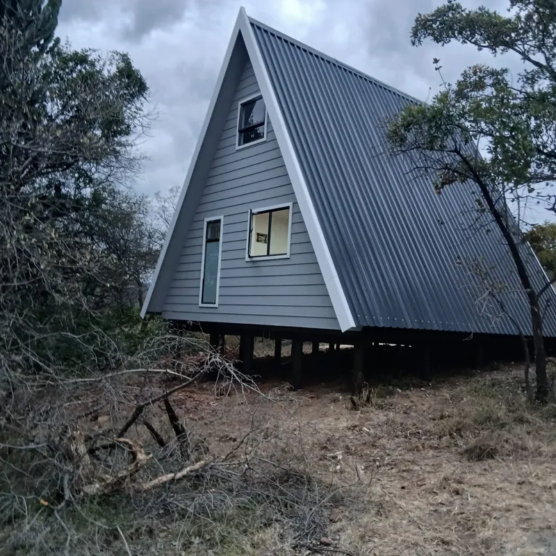 A-frame cabin with a metal roof, raised on poles