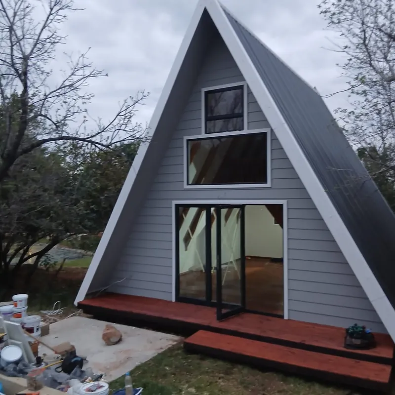 Grey A-frame cabin with a glass front and a timber deck