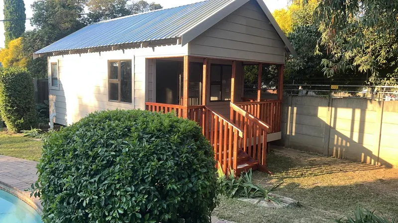 Grey and white Nutec Wendy house with a red timber veranda in a garden