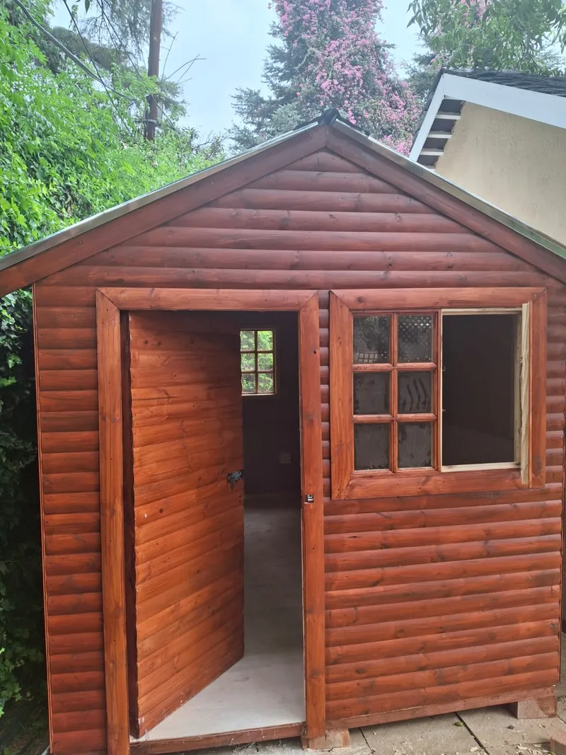 Wooden Wendy house with a panelled door and multi-pane window